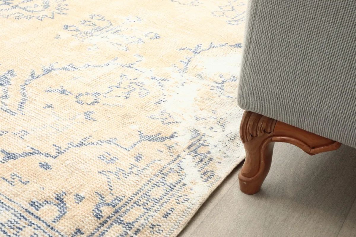 Close-up of the rug next to a sofa leg, demonstrating its placement and scale in a room