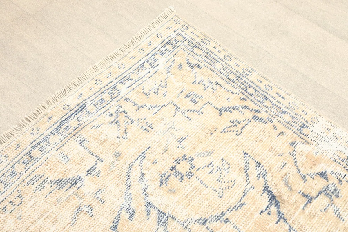 Corner detail of the rug, highlighting the gray border and medallion motifs on the beige field