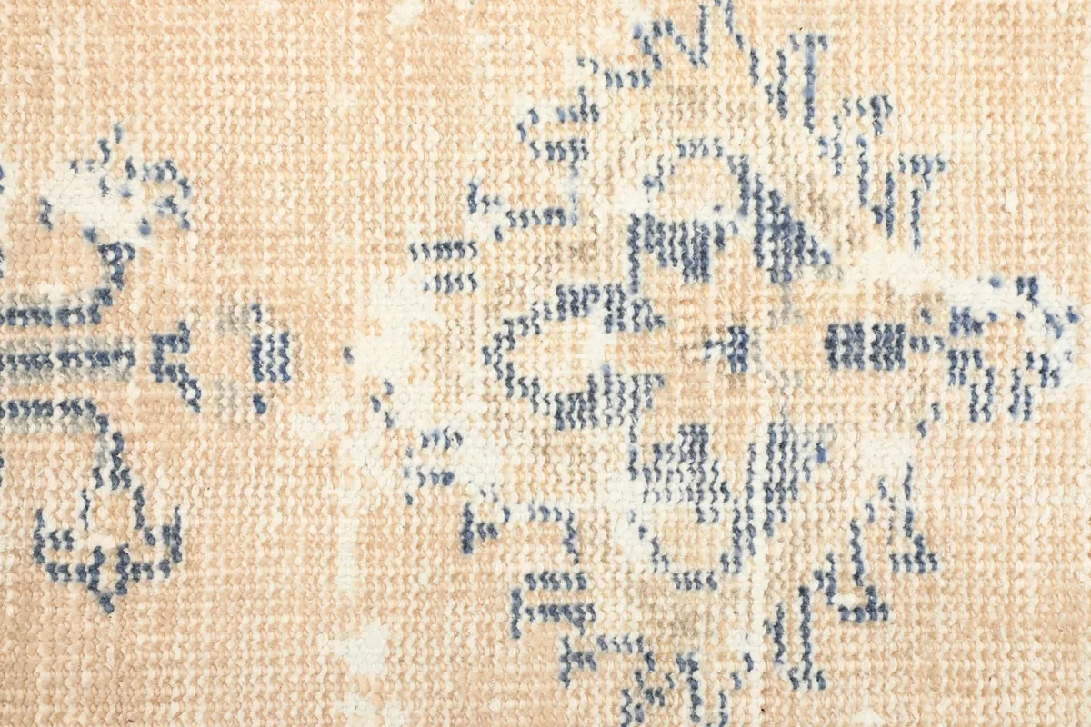 Detailed view of the low wool pile and the intricate, faded gray geometric patterns