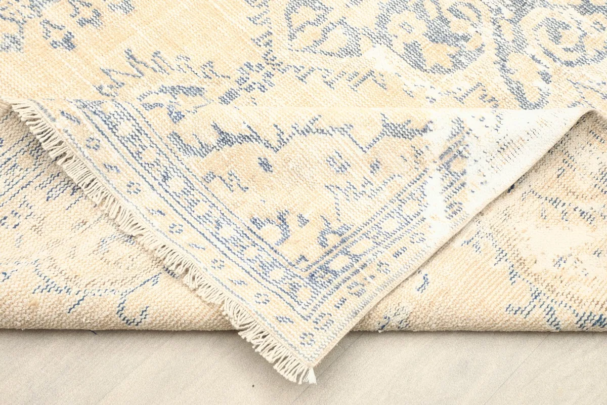 Folded corner of the rug revealing the cotton foundation and the reverse side of the knots