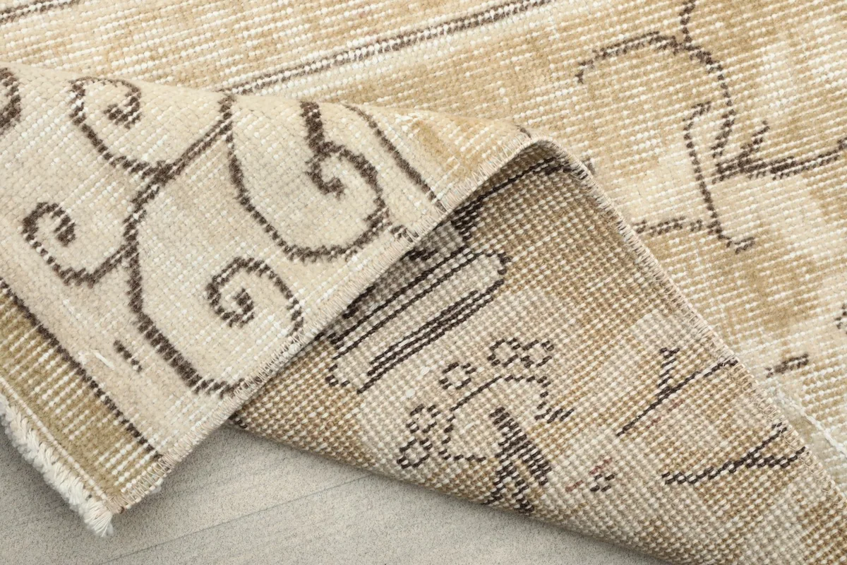 Underside of the rug, revealing the hand-knotted cotton foundation and the back of the wool pile