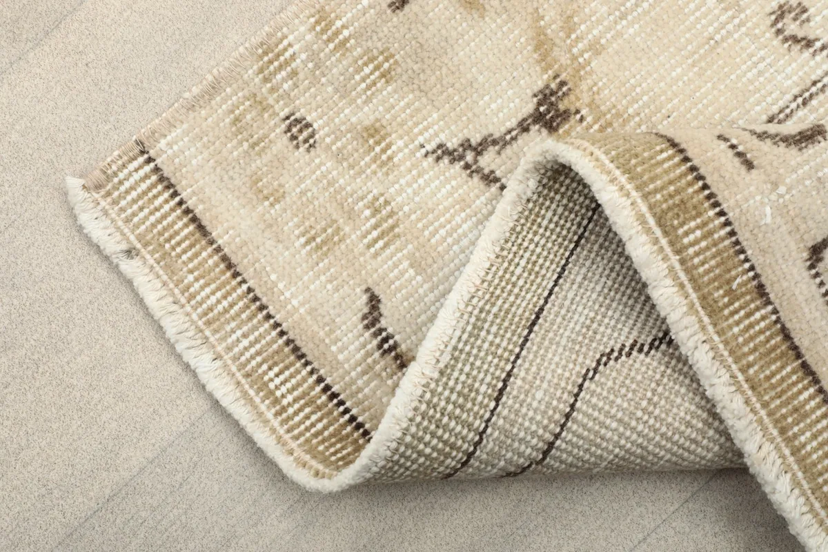 Folded corner of the rug, showing the wool pile on cotton foundation and the finished edge