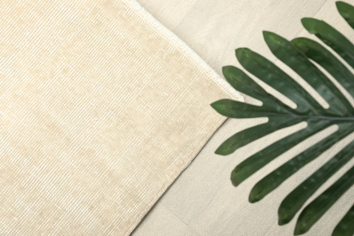 Detail of the rug's texture next to a large green plant leaf