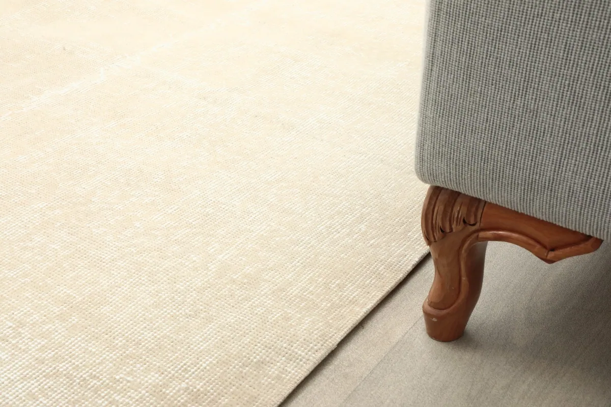 Close-up of the rug's edge next to a sofa leg, showing pile height