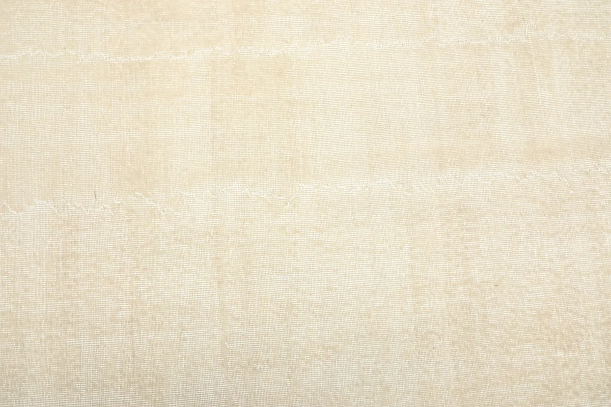 Overhead view of a section of the beige rug, showing its faded, distressed surface