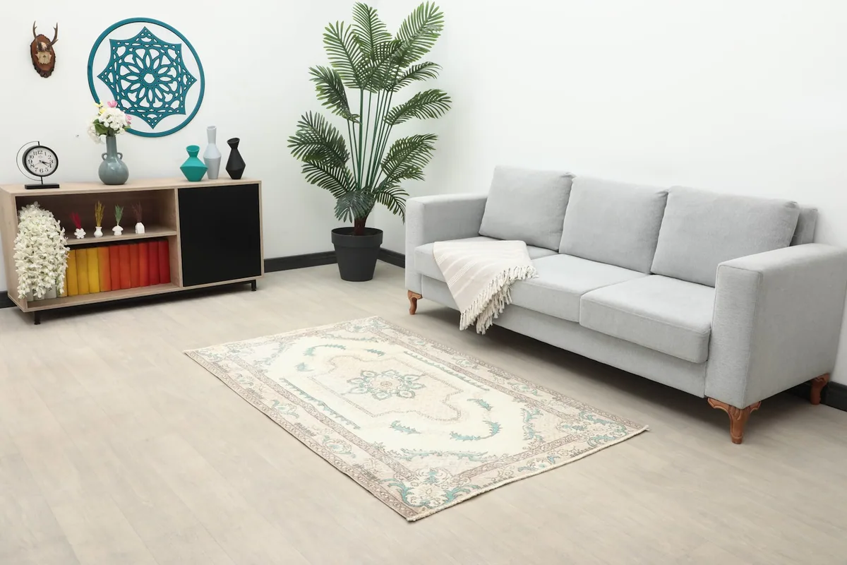 Vintage rug placed in a living room setting with a light gray sofa and console table.