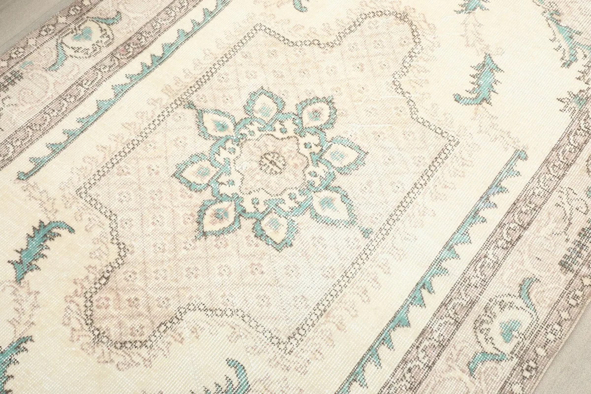 Detailed view of the central medallion and surrounding patterns in cream, green, and beige.