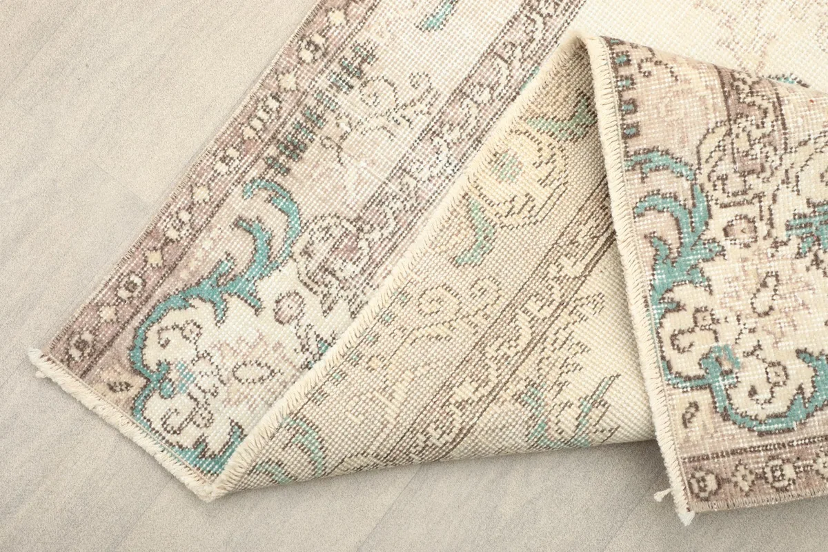 Folded section of the rug, showing the wool pile and cotton foundation from the side.