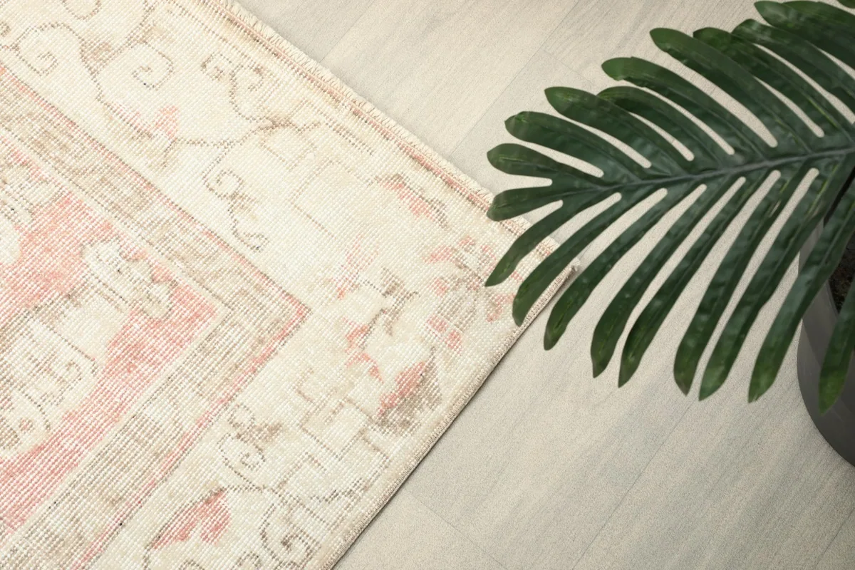 Side view of the rug's border, with a plant in the foreground, emphasizing its decorative edge.