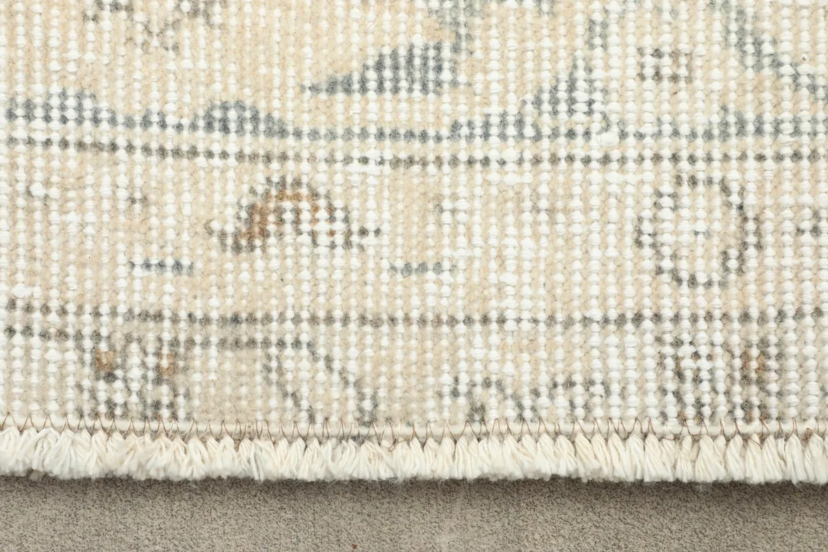 Close-up detail of the rug's short fringe and the faded blue and beige patterns