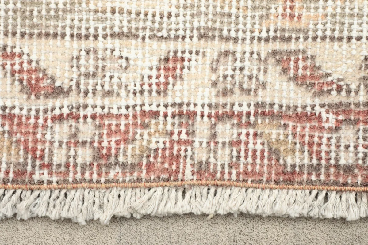 Close-up of the short, natural cotton fringe and edge of the hand-knotted rug