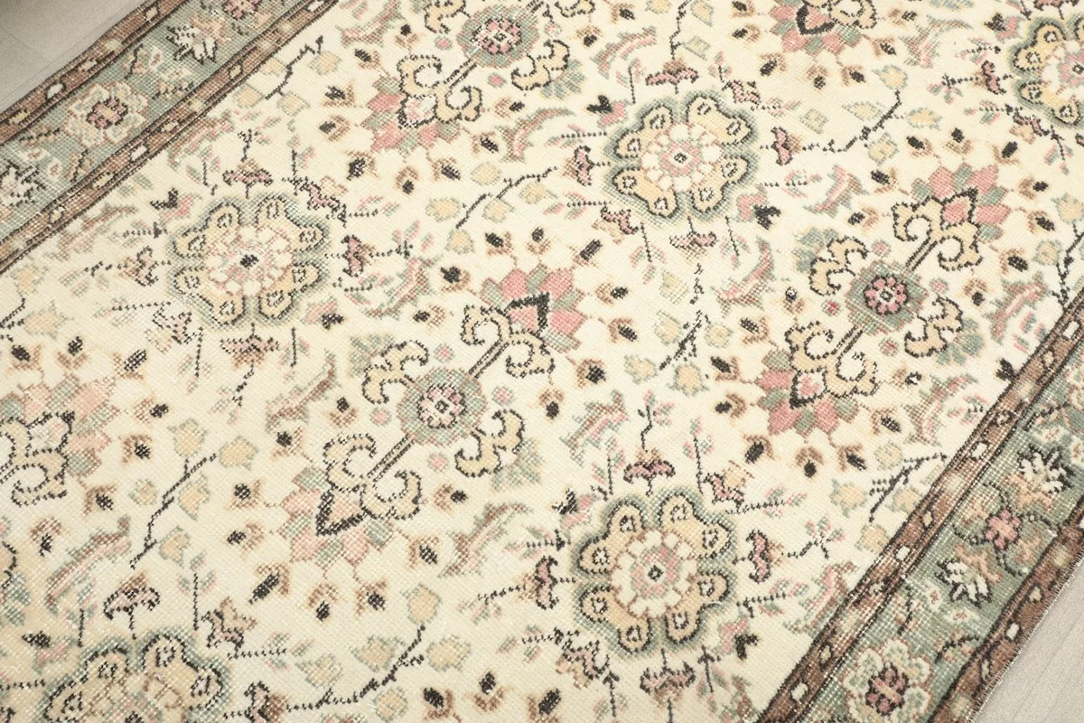 Close-up of the ivory rug's field with rose, green, and tan floral patterns
