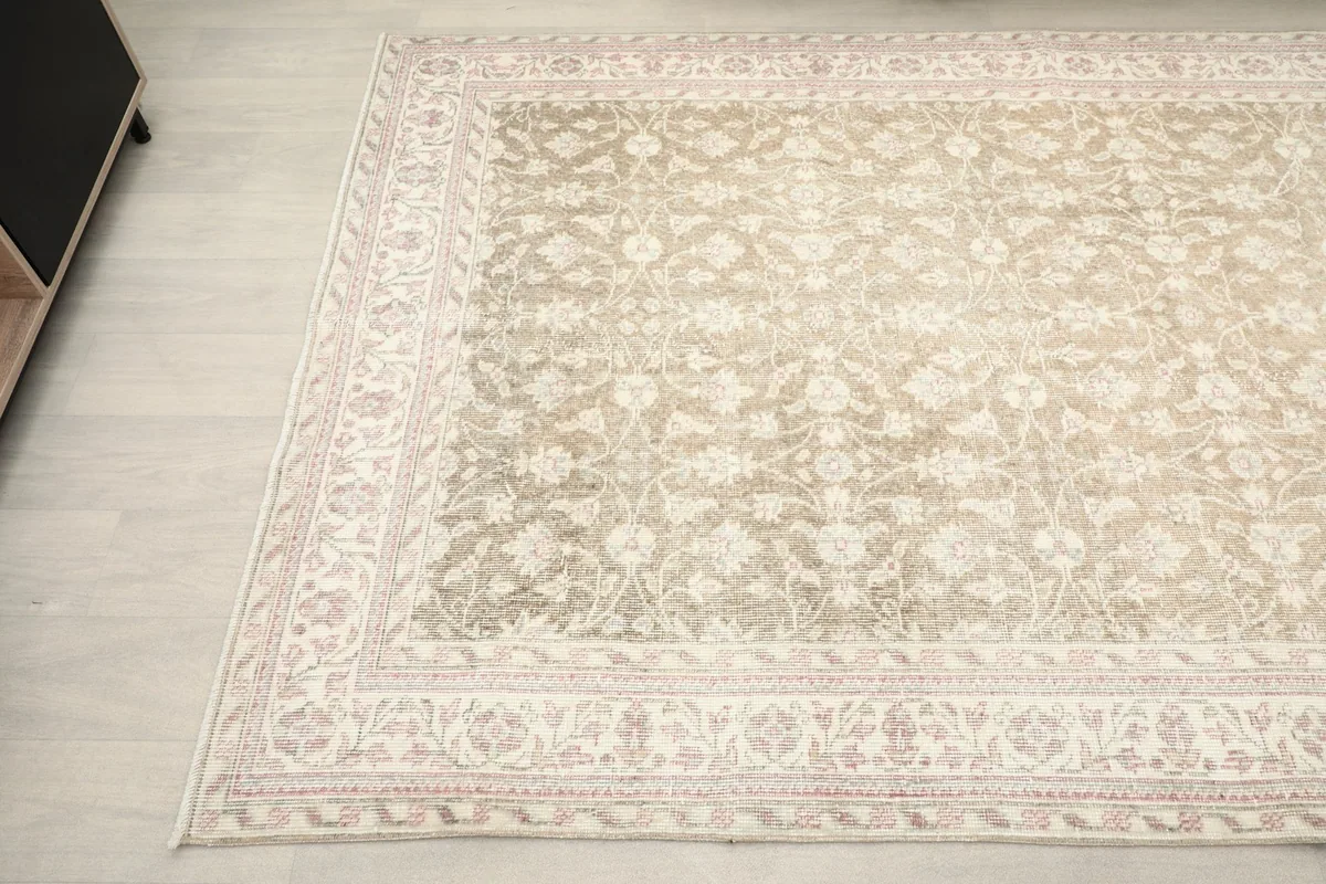 Corner view of the rug, capturing the interplay of beige, ivory, and rose tones in the design