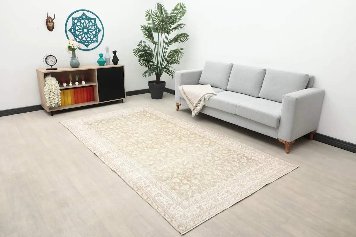 Beige floral rug placed in a living room setting with a gray sofa and modern decor