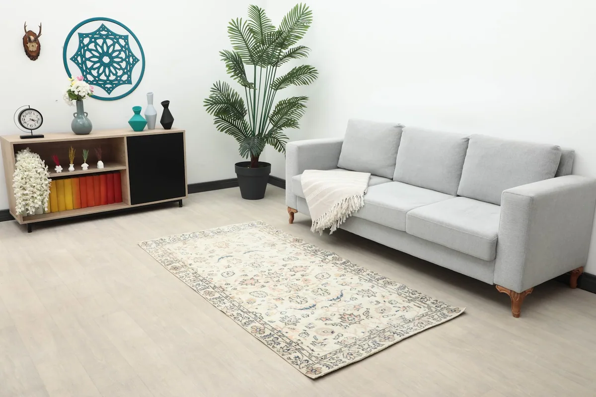 Ivory floral rug in a modern living room setting with a gray sofa and wooden console