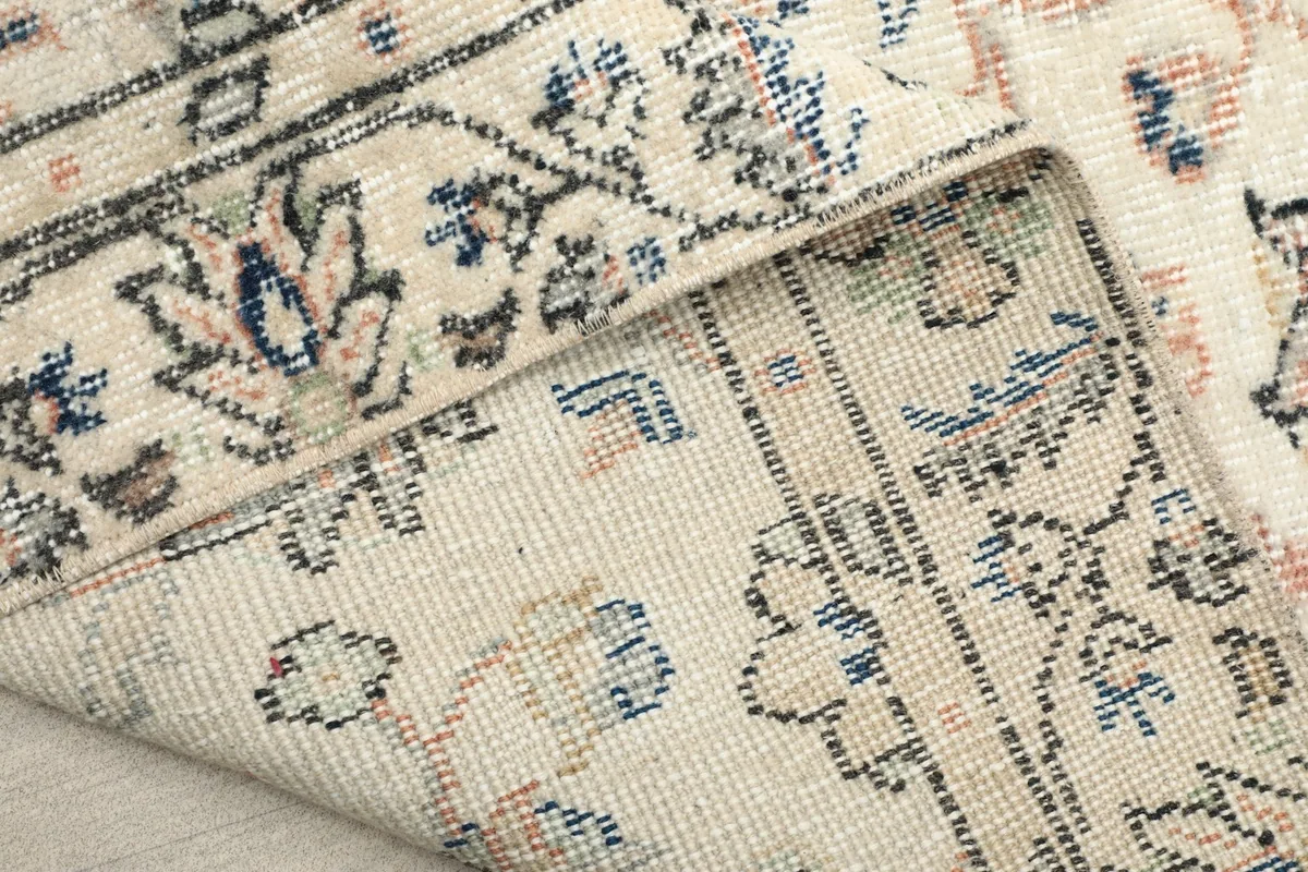 View of the rug's underside and folded edge, revealing the cotton foundation