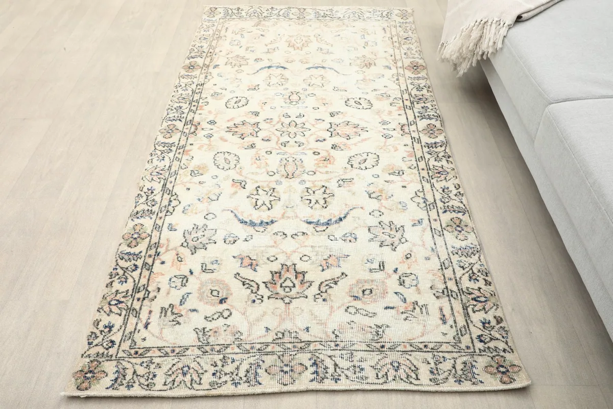 Overhead view of the ivory area rug placed on a light wooden floor in a room setting