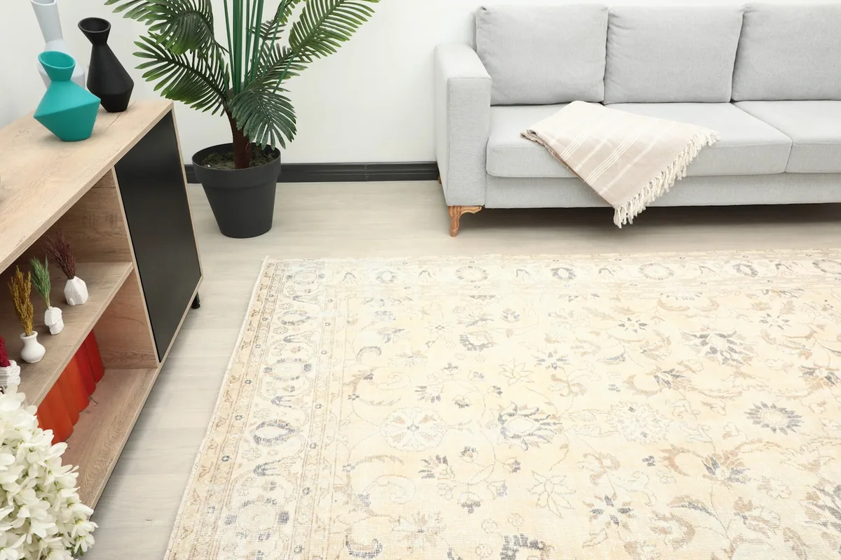 View of the rug in a room setting, focusing on its placement relative to a sofa and cabinet.