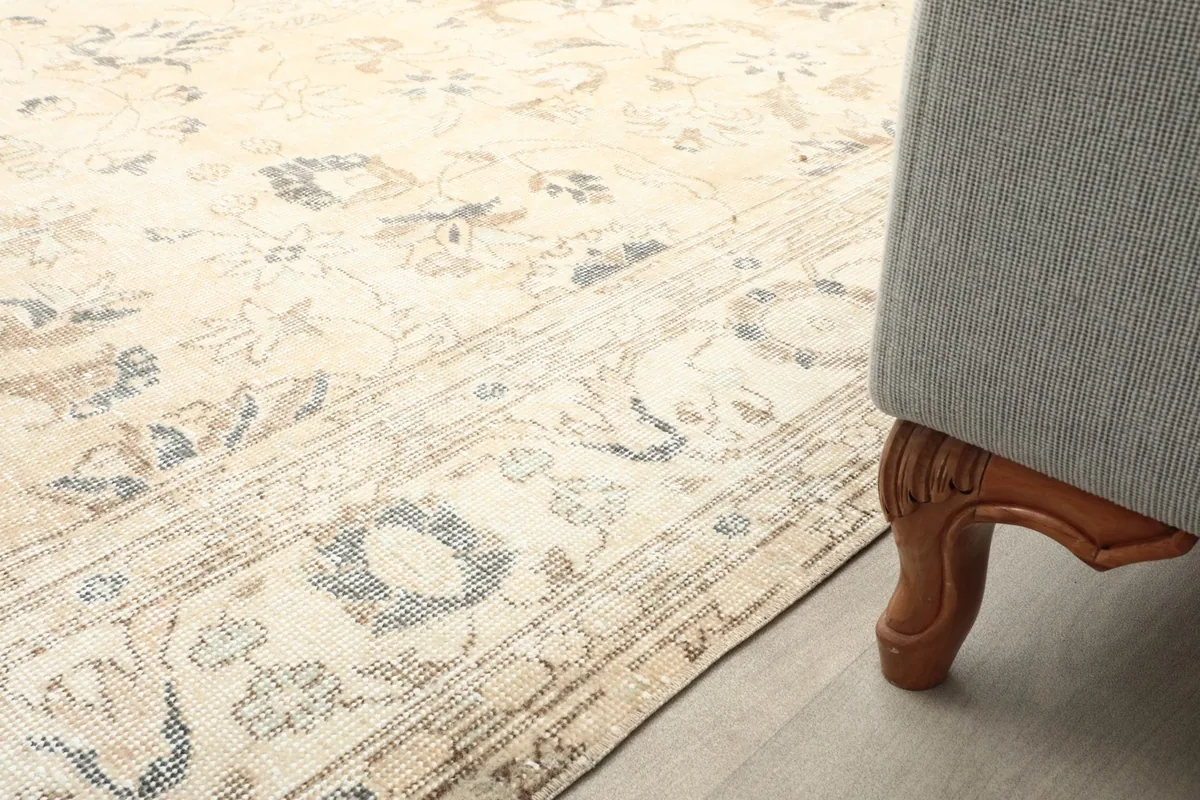 Partial view of the rug's border and field next to a wooden sofa leg in a room setting.
