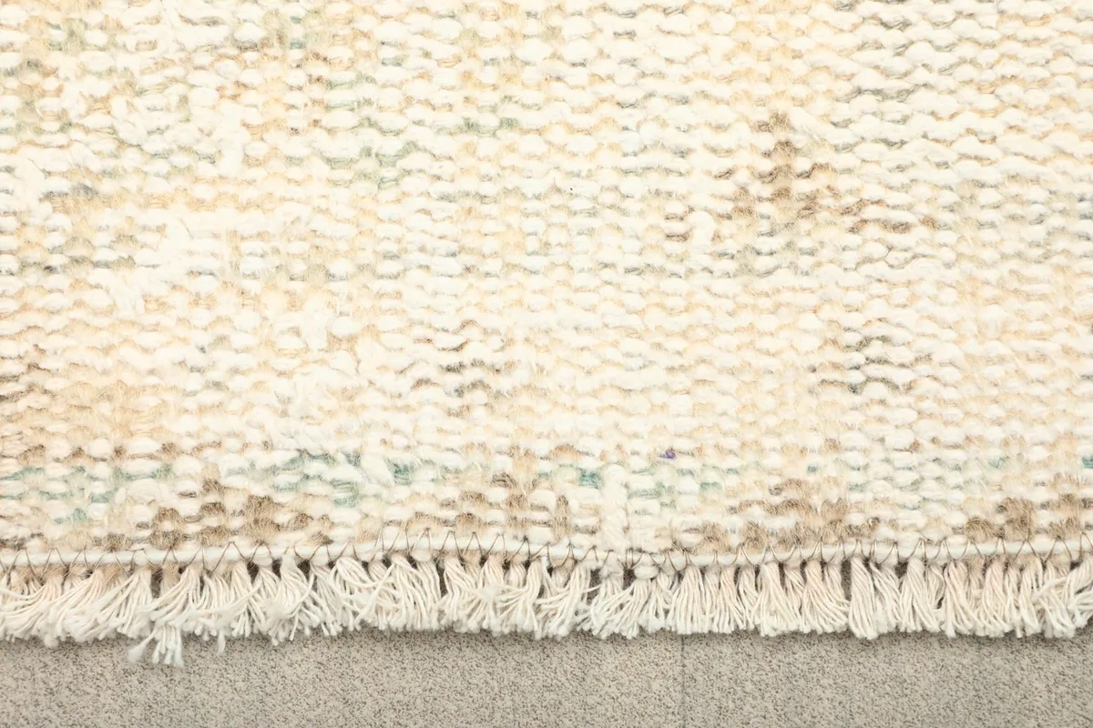 Close-up of the short, natural fringe and the faded wool pile texture of the rug