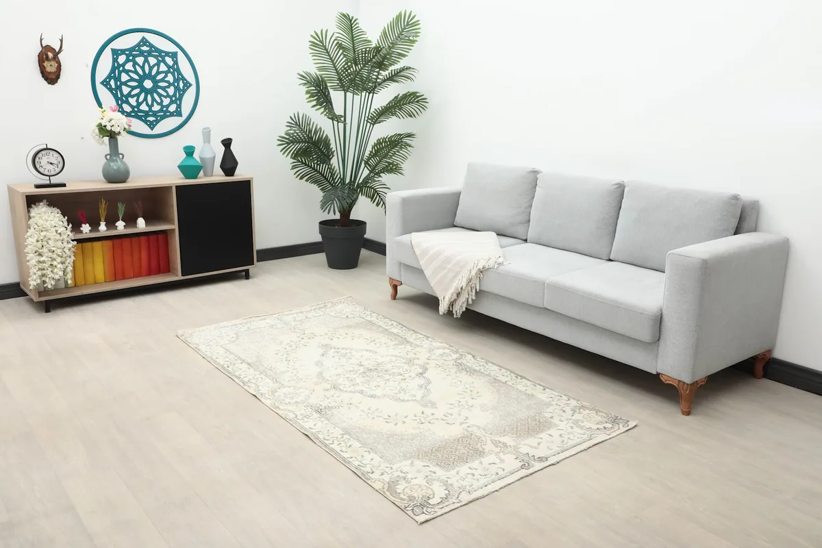 Vintage Anatolian rug displayed in a living room setting with a gray sofa and wooden console.