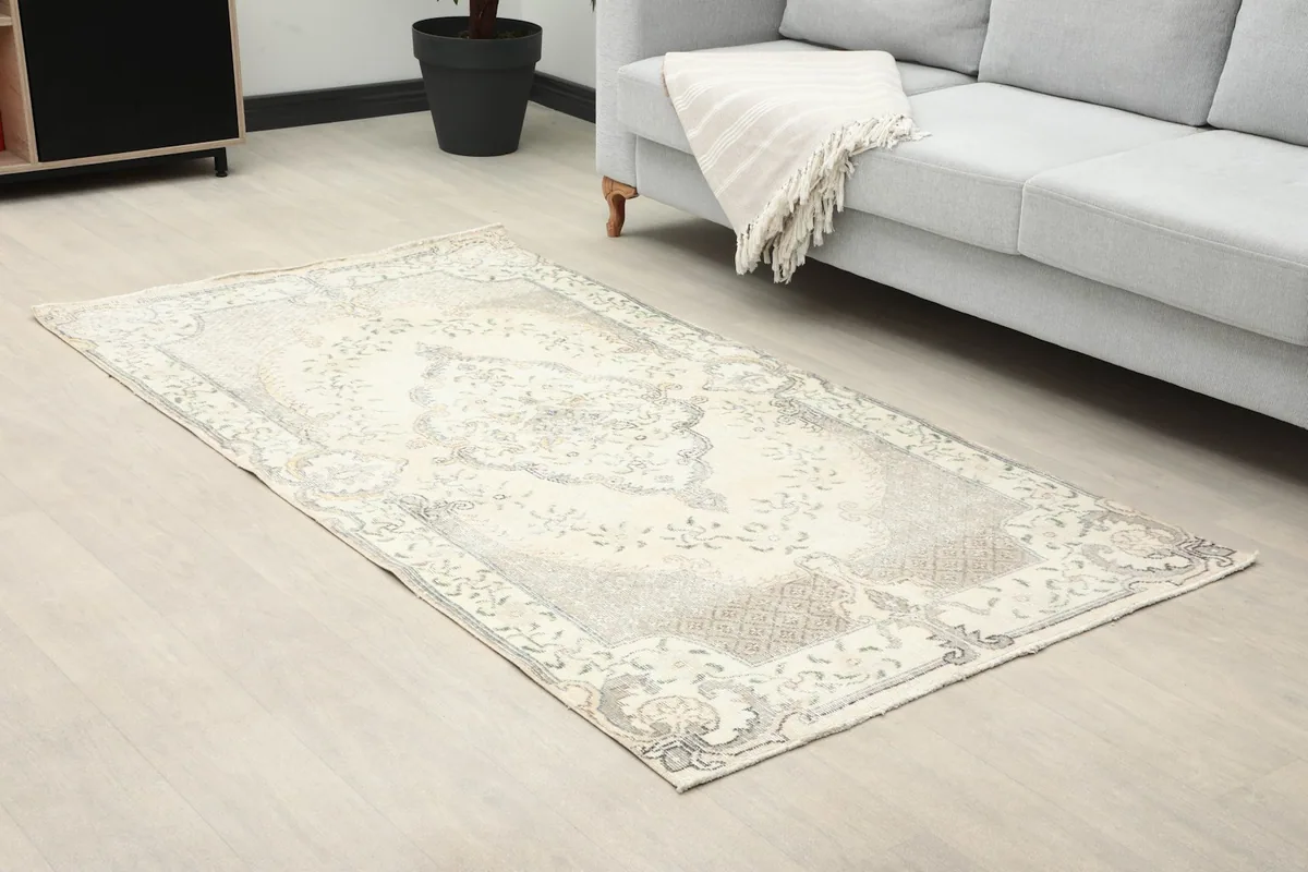 Angle view of the ivory and gray vintage rug in a living room, showing its placement by a sofa.