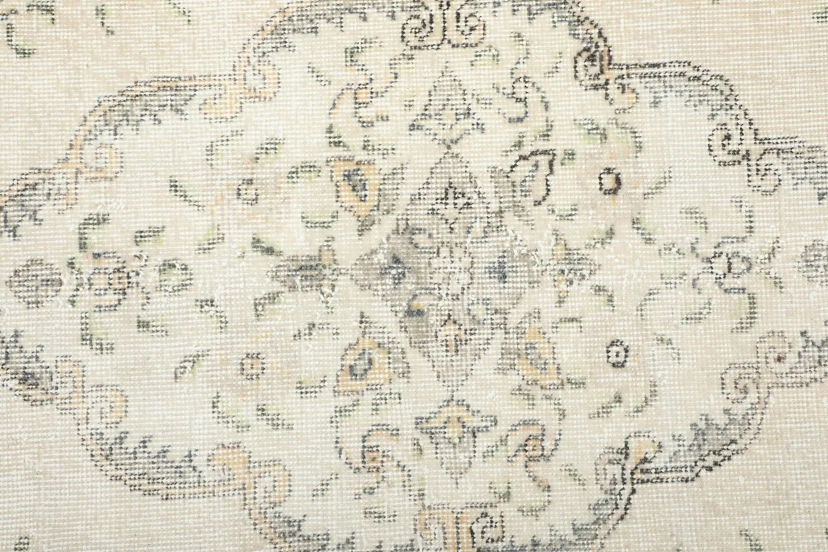 Macro view of the rug's central design, showing the faded colors and texture of the wool pile.