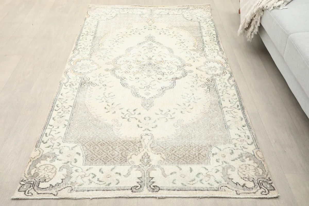 Overhead view of the vintage Anatolian rug with ivory and gray tones laid on a light wood floor.