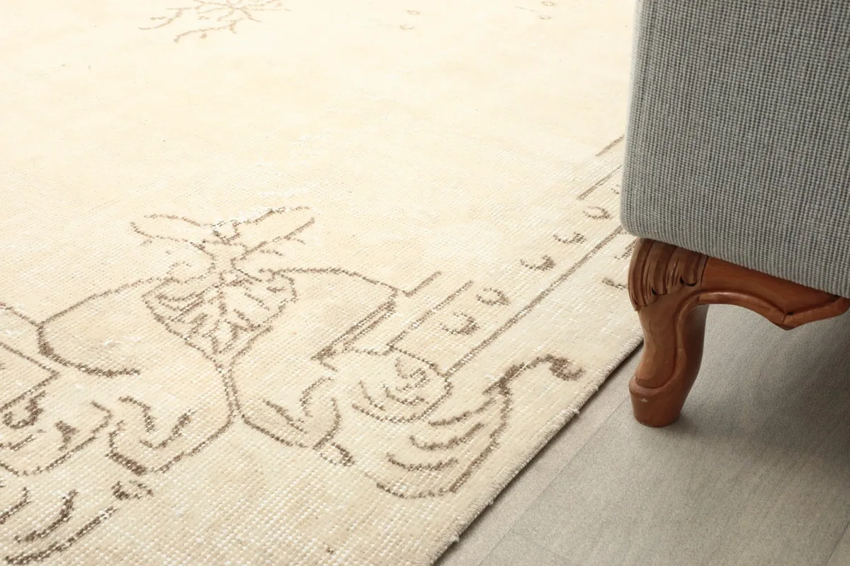 Close-up of the rug's border pattern next to the leg of a gray sofa.