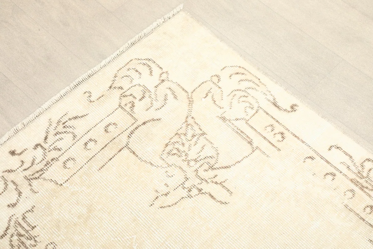 Corner detail showing the faded beige border design on the cream field.