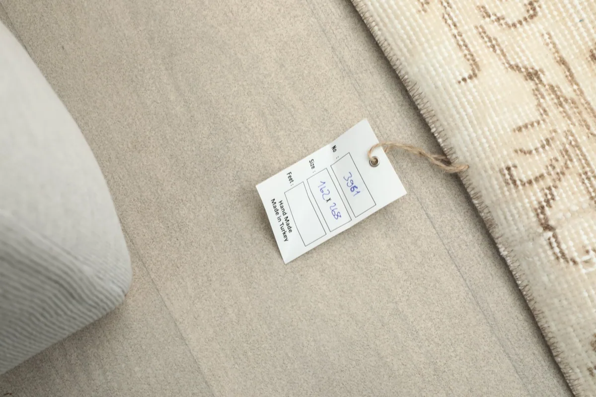 Rug label next to the cream area rug on a light floor, showing product information.