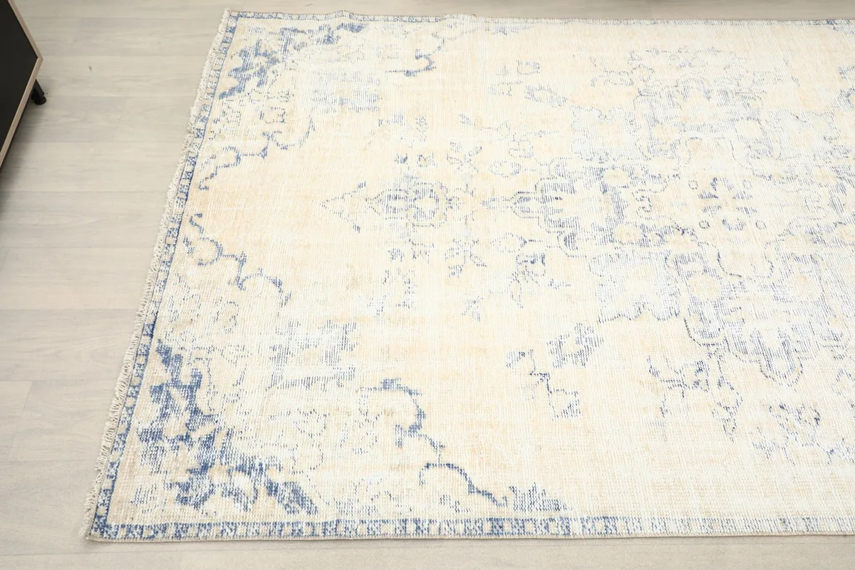 Corner detail of the vintage rug, highlighting the faded blue border and main field