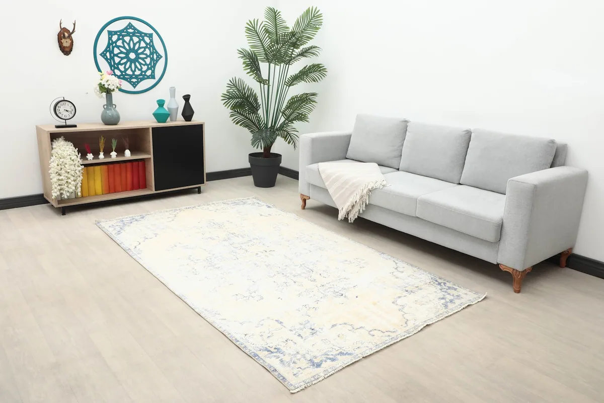 Vintage Anatolian rug displayed in a living room with a gray sofa and wooden cabinet