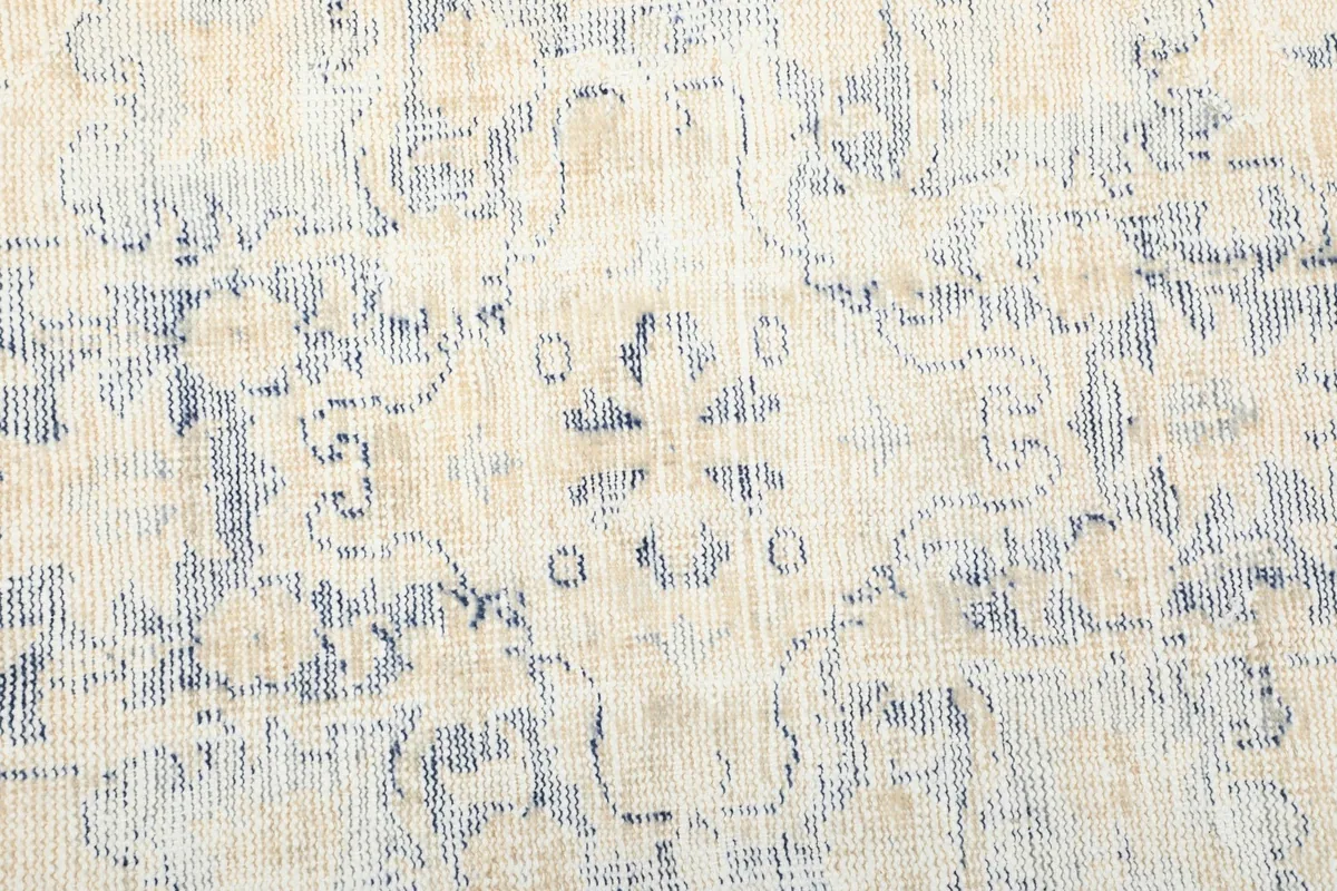 Close-up of the hand-knotted texture and faded blue geometric motifs within the rug