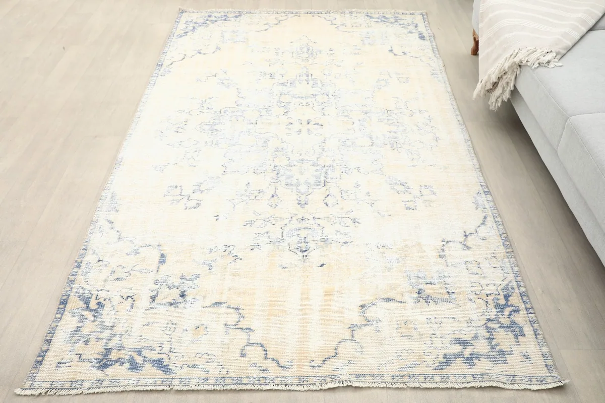 Overhead view of the ivory and blue vintage rug in a room setting next to a sofa