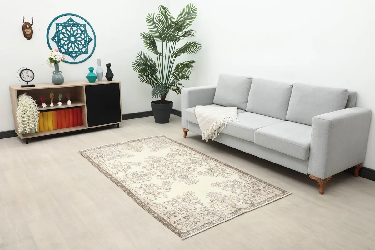 Wide shot of the ivory and brown Anatolian rug in a living room setup with a sofa and side cabinet.