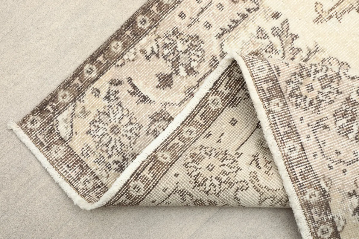 View of the vintage rug folded, showing the back of the cotton foundation and the wool pile.