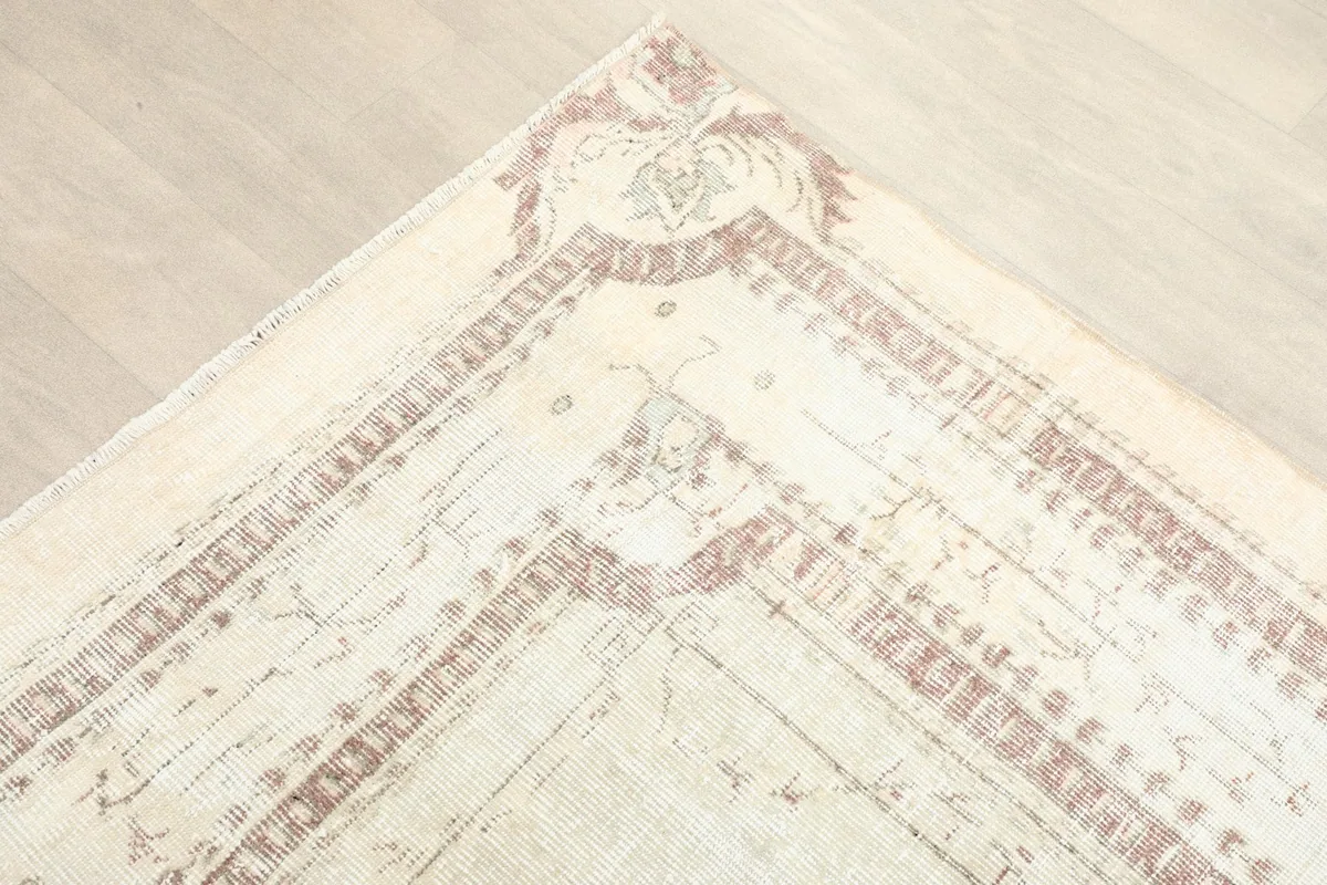 Detail of the corner border showing faded rose and cream geometric and botanical patterns