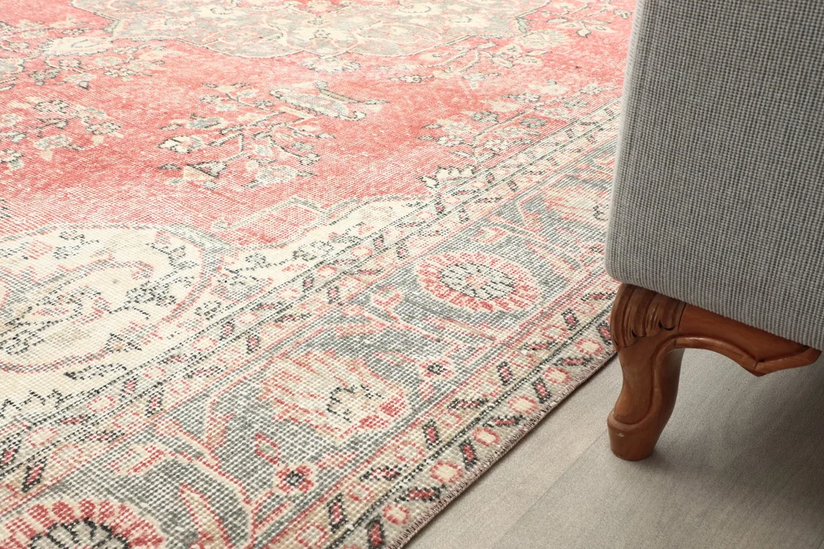 Side view of the rug next to a sofa leg, showing the border design and how it complements the room