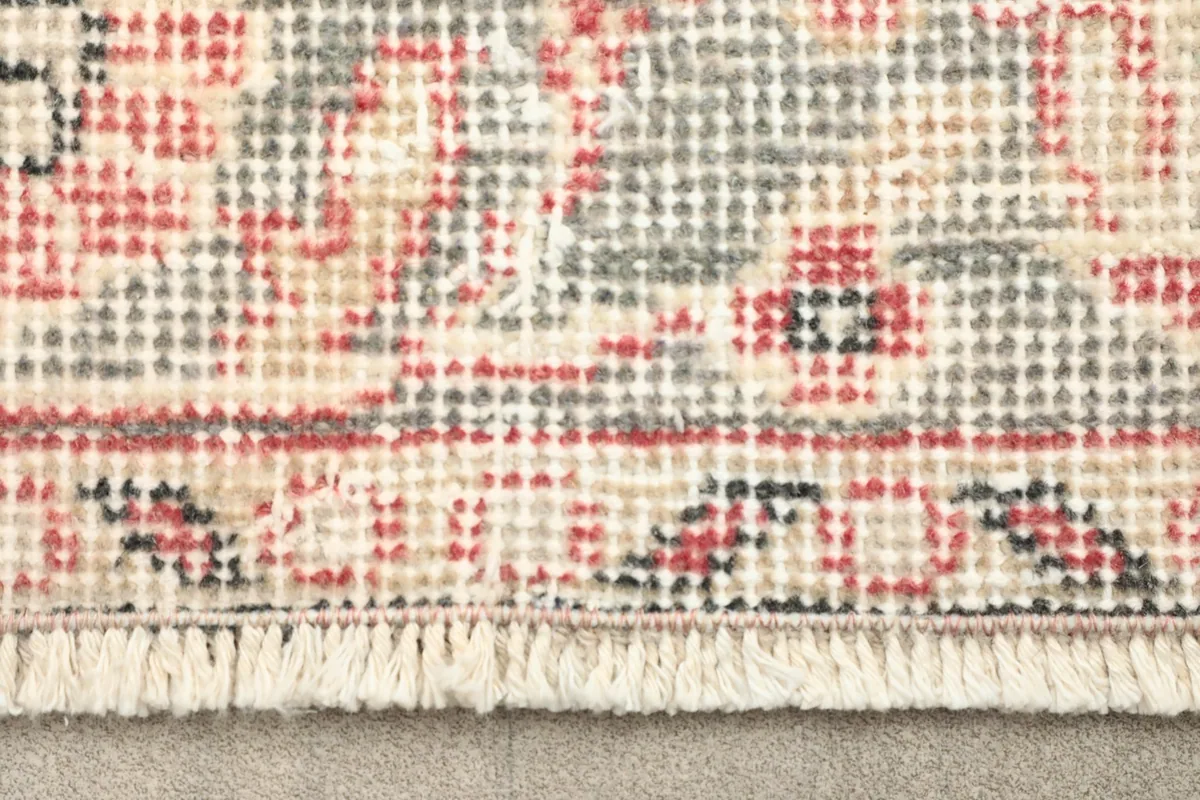 Close-up of the rug's fringe and a section of the border with rose and gray details
