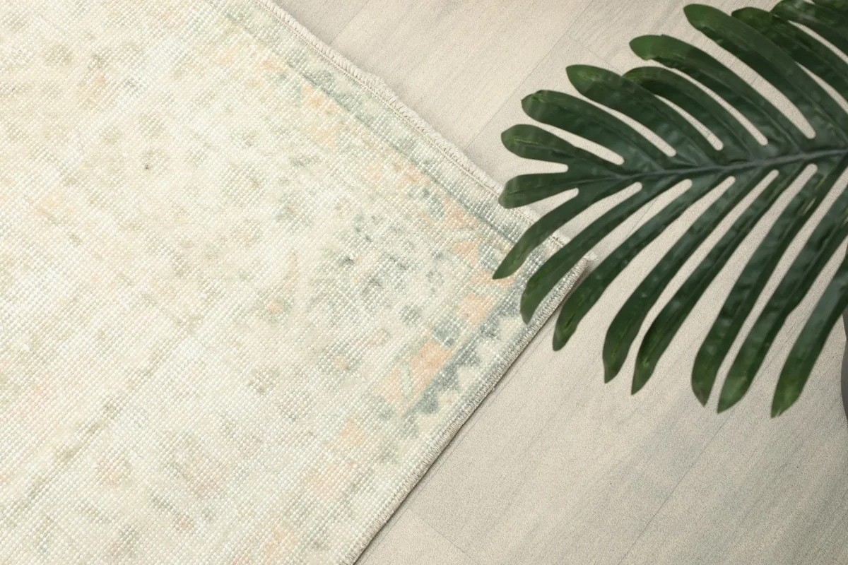 Angled view of the rug's surface and border, with a plant leaf in the foreground