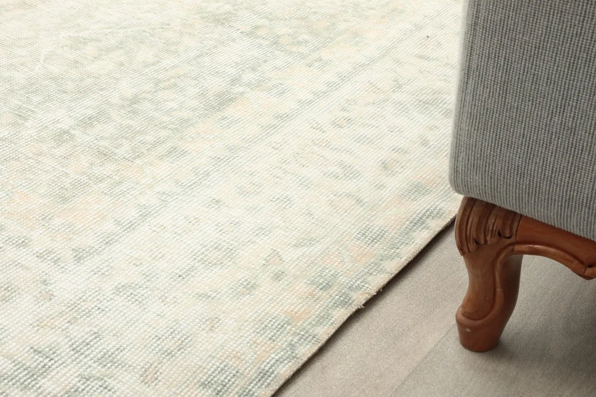Detailed view of the rug's border and corner next to a wooden furniture leg