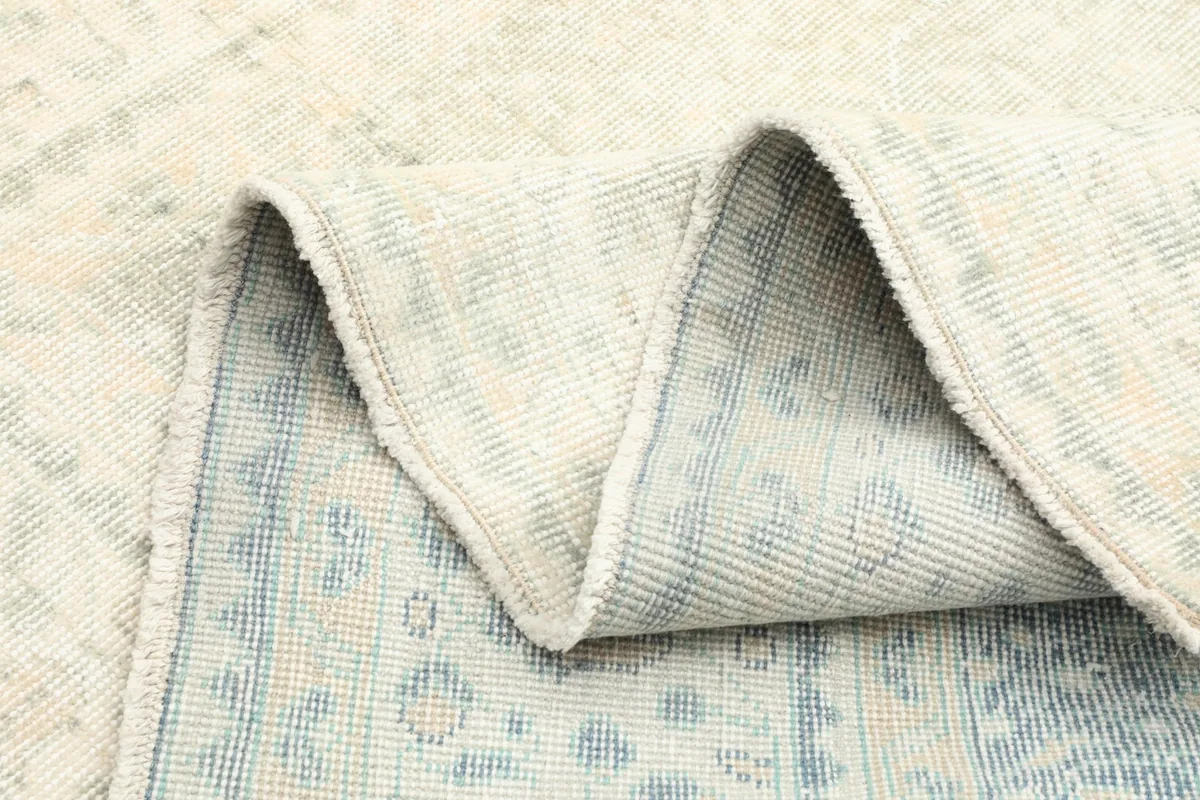 Multiple folds of the rug showing the back of the cotton foundation and weave