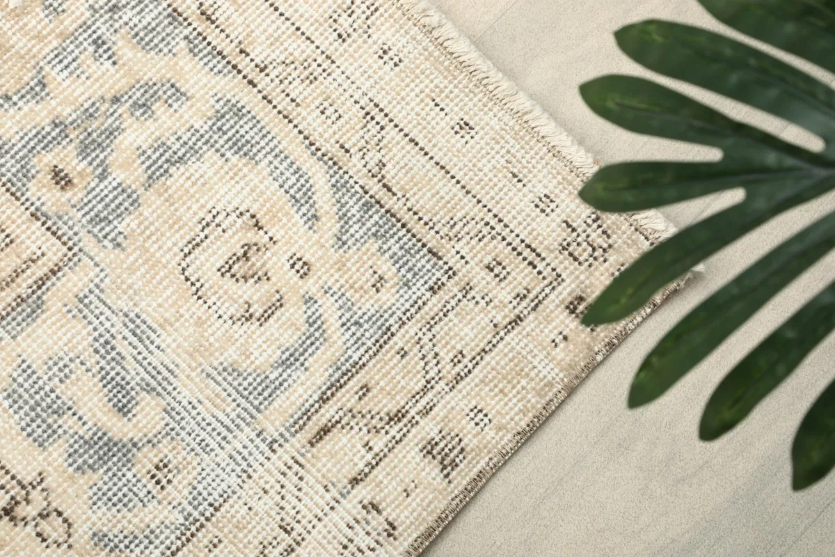 Corner detail of the rug's border and fringe, with a green leaf accent.