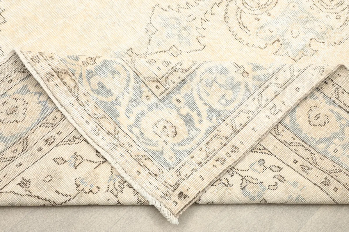Folded corner of the rug revealing the cotton foundation and reverse side of the knotting.