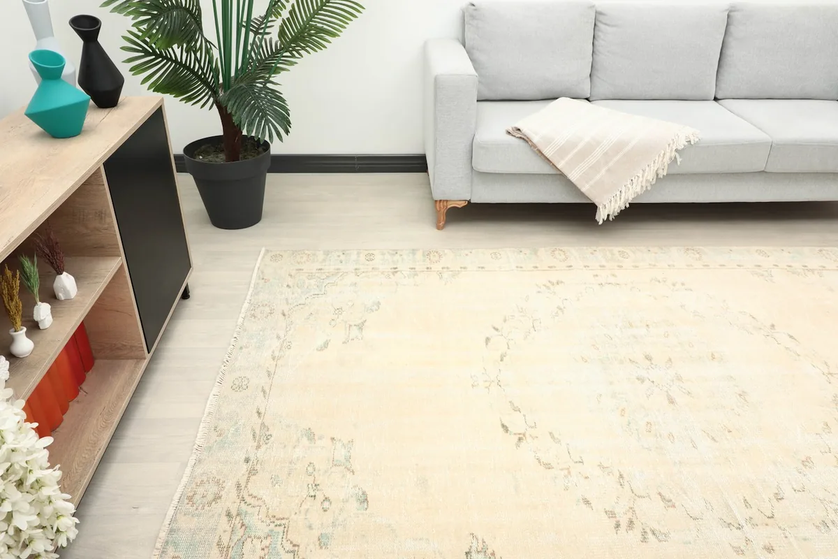 Another room view of the rug, capturing its muted tones and vintage appeal near a sofa