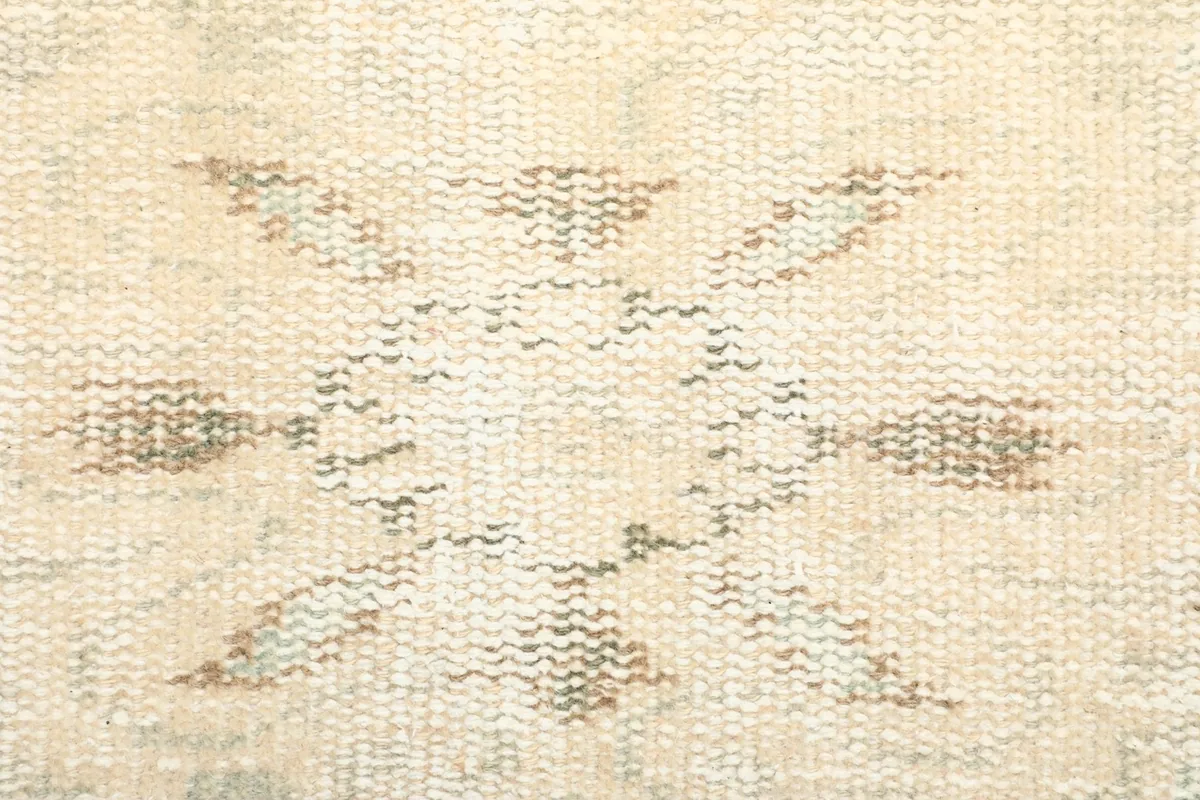 Extreme close-up showing the low pile and hand-knotted wool texture of the rug