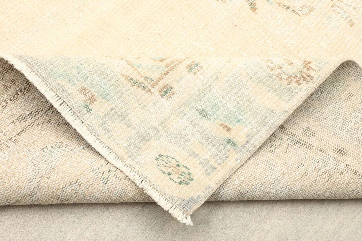 Folded corner of the rug revealing the cotton foundation and the reverse side of the knots