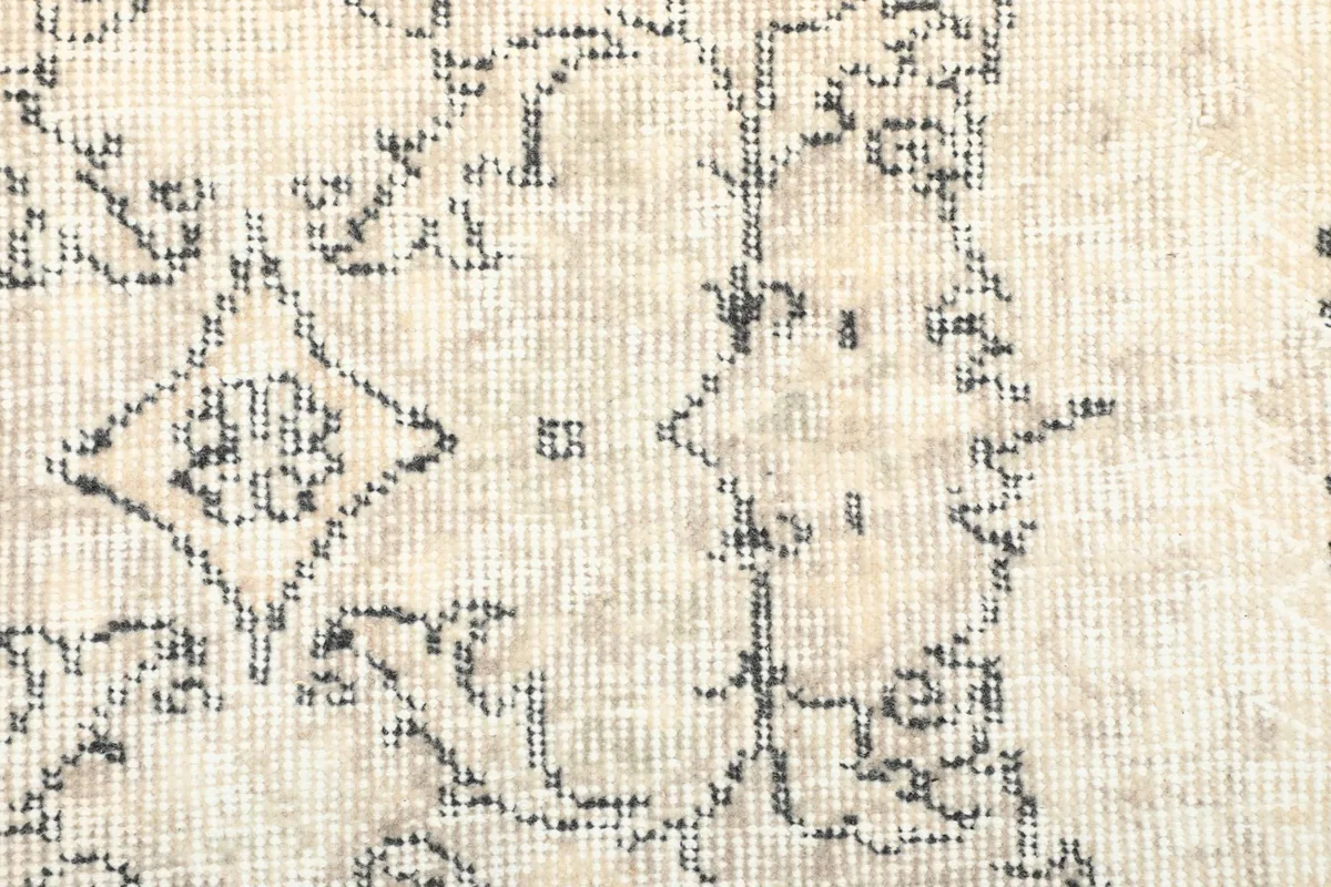 Detailed view of the low wool pile and the intricate, faded patterns of the rug