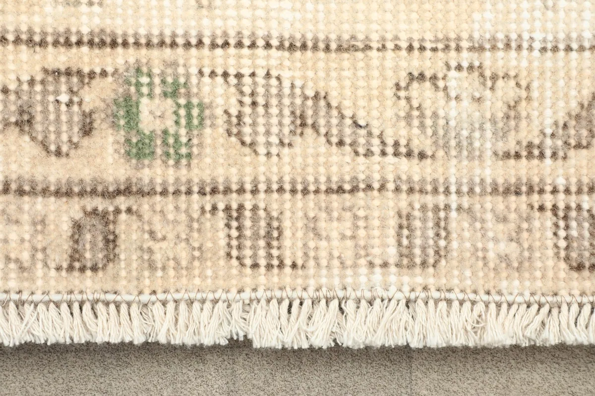 Close-up of the rug's fringe and a section of the border pattern with subtle olive green accents